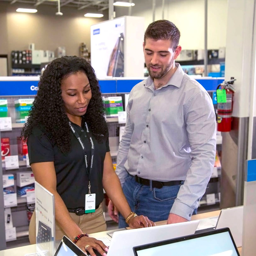 Two people looking at a laptop and talking in store