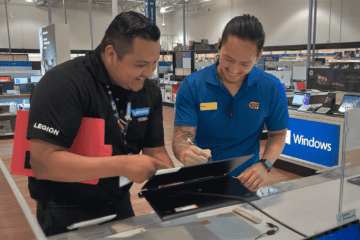 Two men standing at an ipad talking