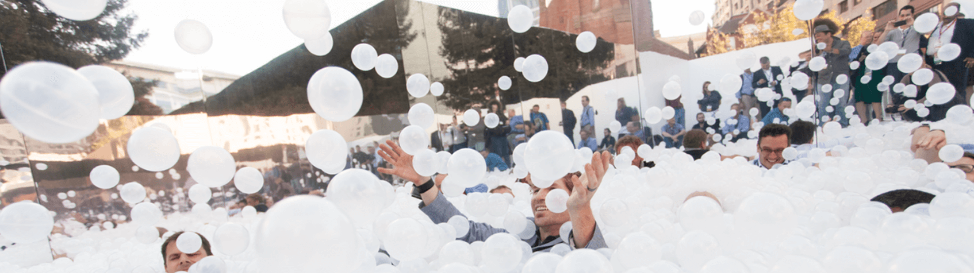 Art installation of people in a mirrored courtyard surrounded by beachballs